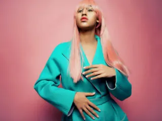 high fashion black model with pink hair and teal jacket representing 2626 angel number meaning manifestation