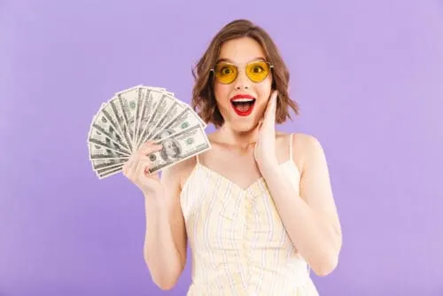 cute woman holding up cash money she manifested