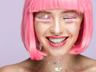 cute glittery girl in a pink wig and pink lashes with 6464 glitter pieces, taking inspired action toward her goals.