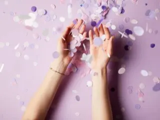 purple confetti raining down on hands in celebration of angel number 111 success