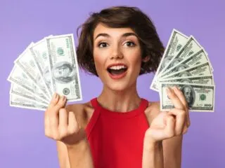 happy short haired girl on a purple background holding two stacks of money in her hands