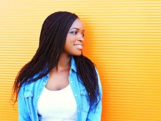 pretty black woman with braids on a yellow background and jean jacket