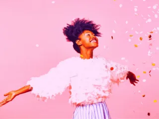 excited black woman with pink glitter falling all over her